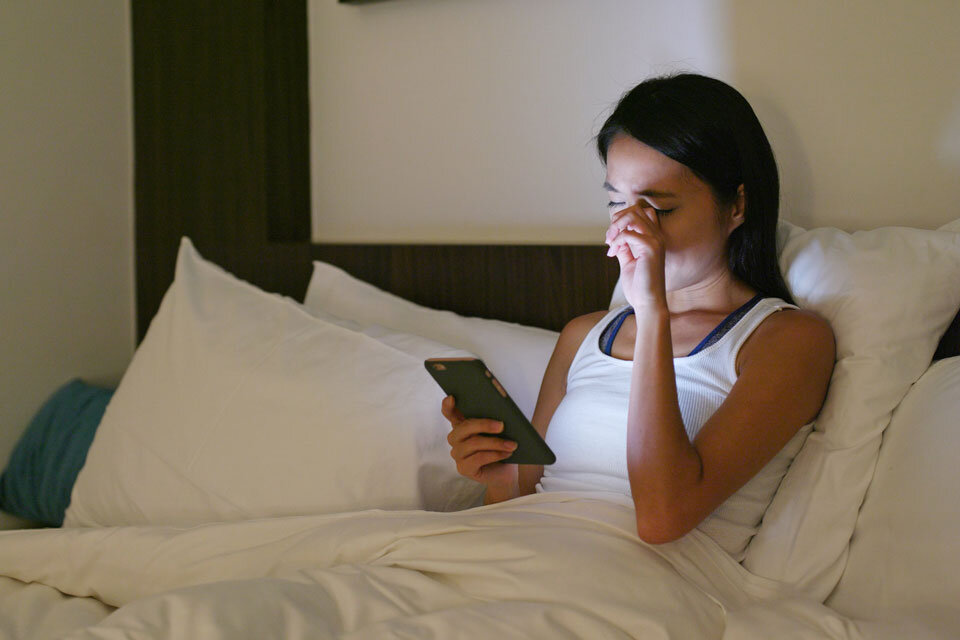 夜間にスマートフォンを使用する女性の画像
